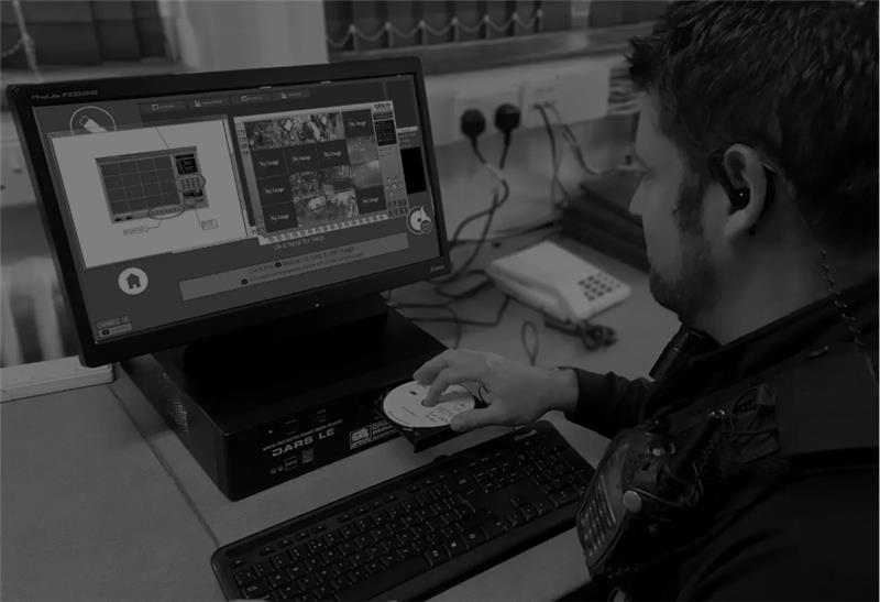 Operator using forensic computer at workstation with security footage displayed.